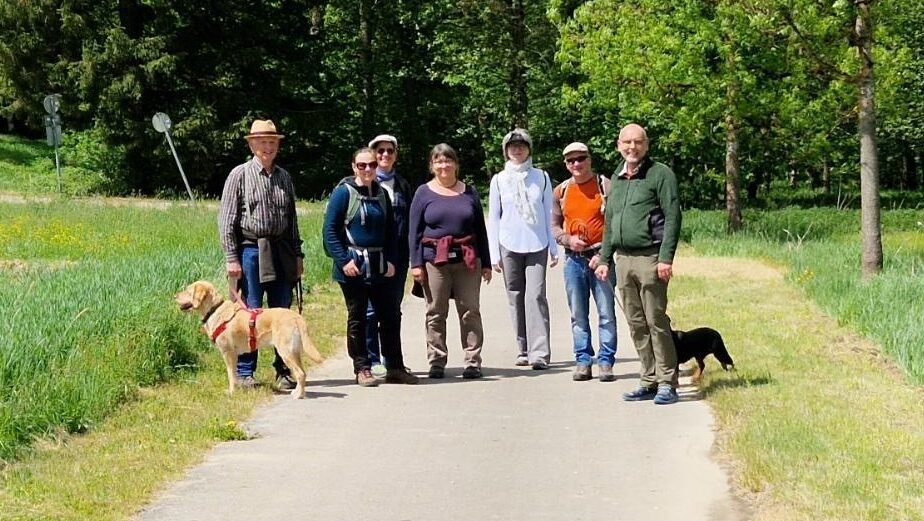 Das Foto zeigt die Teilnehmer:innen der Frühjahrswanderung. Im Hintergrund sieht man den Weltwald.